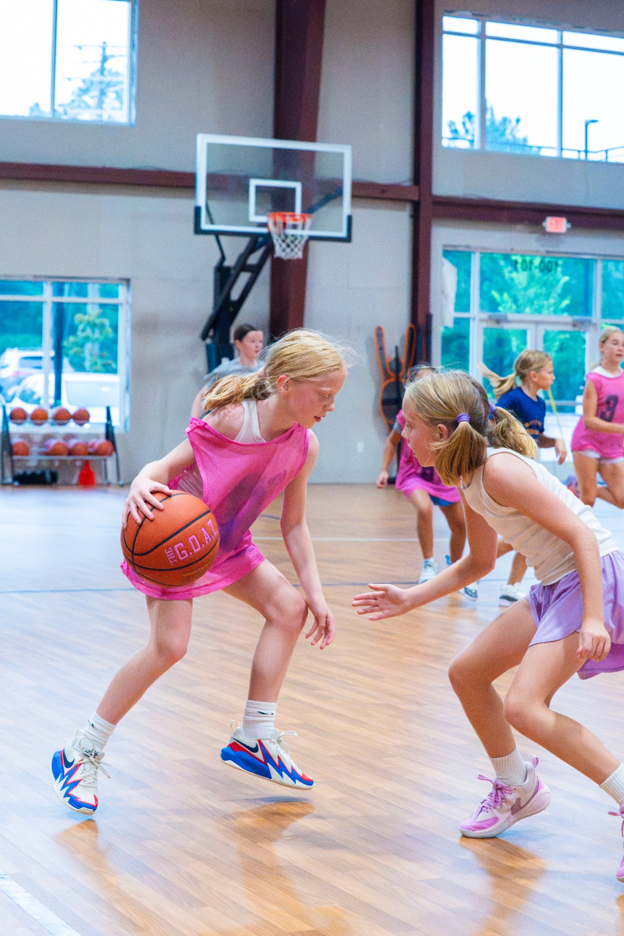 Player in a pink pinnie protecting the ball as a defender pressures on the wing