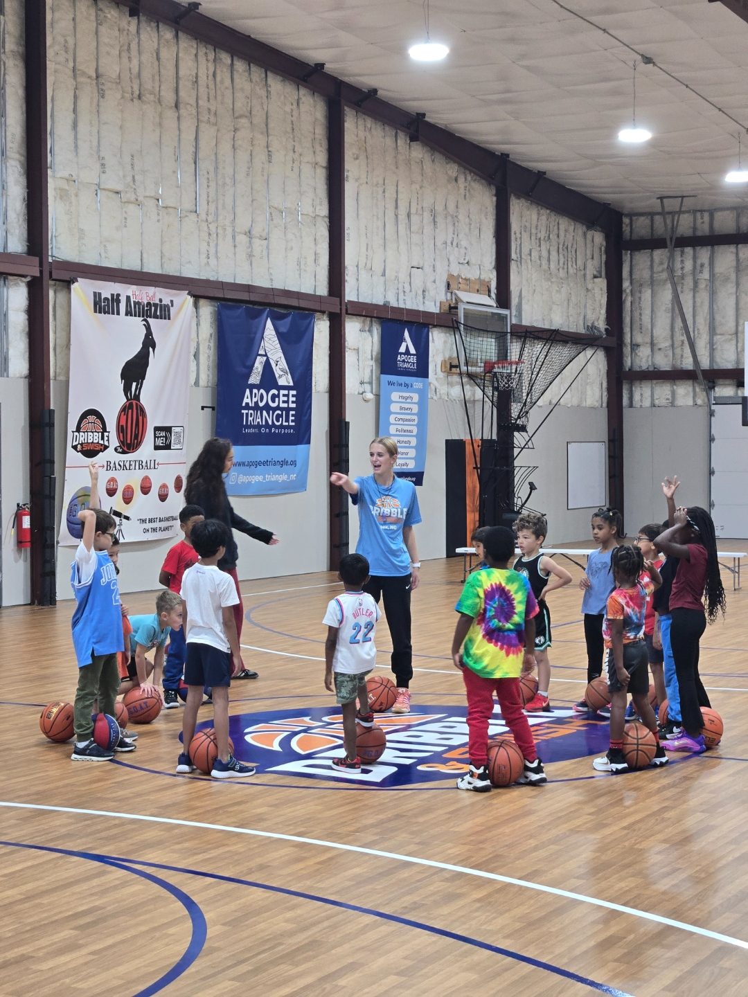 Coach leading a full group huddle at center court during a training session at Dribble & Swish