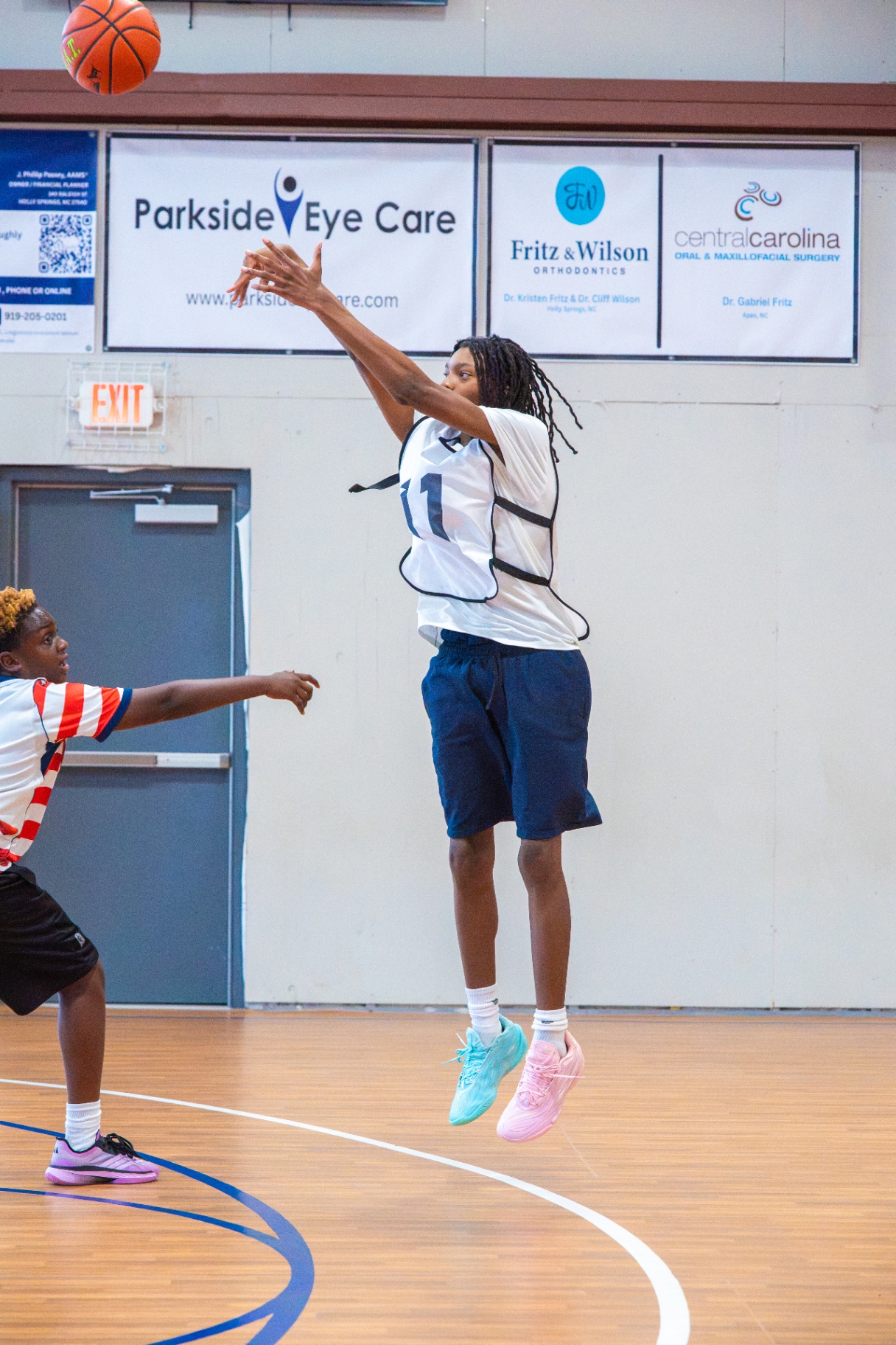 Player releasing a jump shot in front of the sponsor banner wall