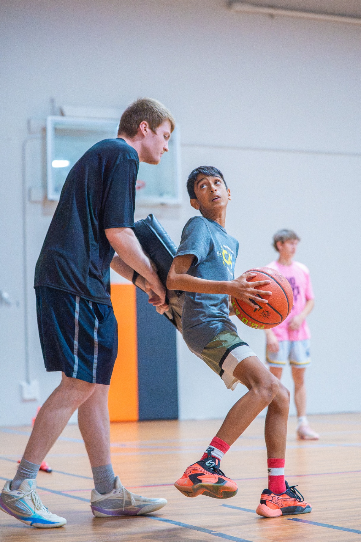 Coach applying a contact pad while a player finishes through defense during a training rep