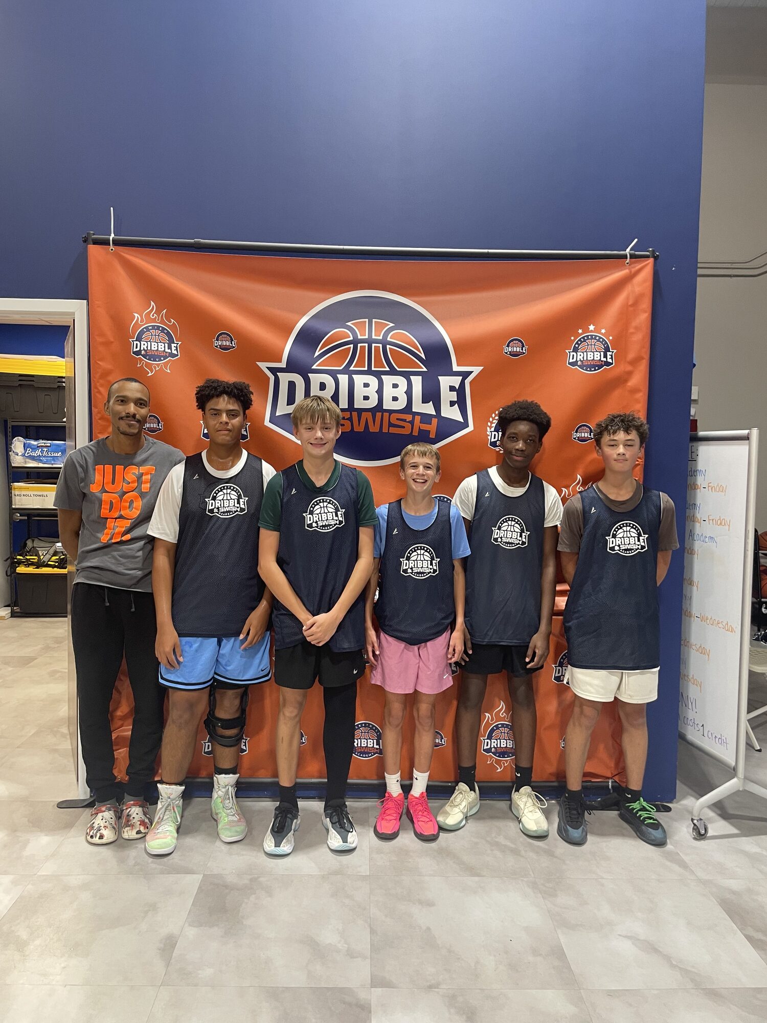 Academy athletes and coach lined up in pinnies in front of the Dribble & Swish banner