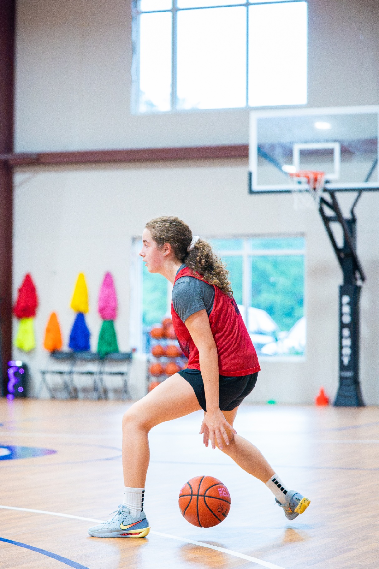 Player in a red pinnie working a low crossover in front of the hoop