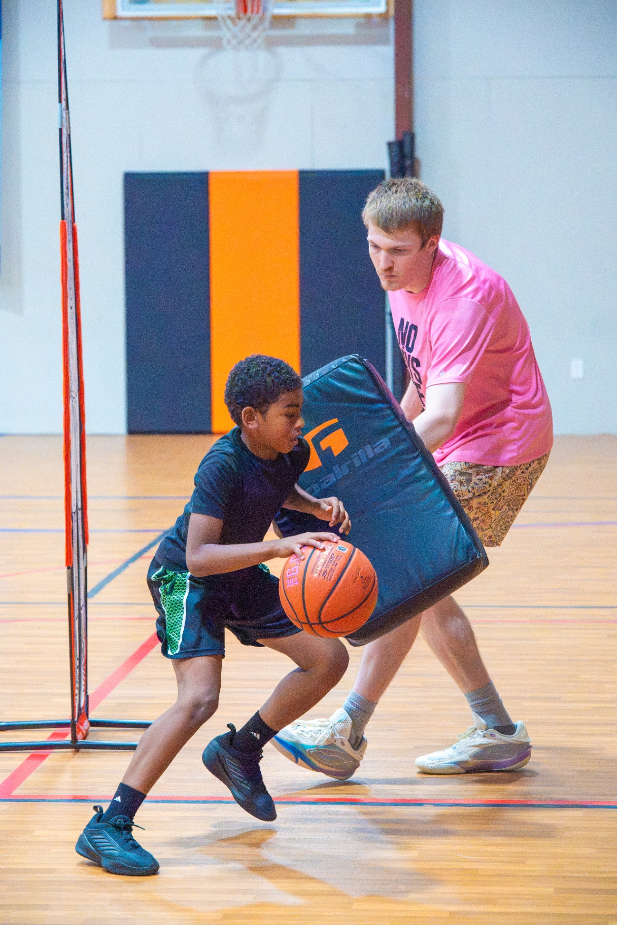 Young player attacking the paint against a coach with a contact pad