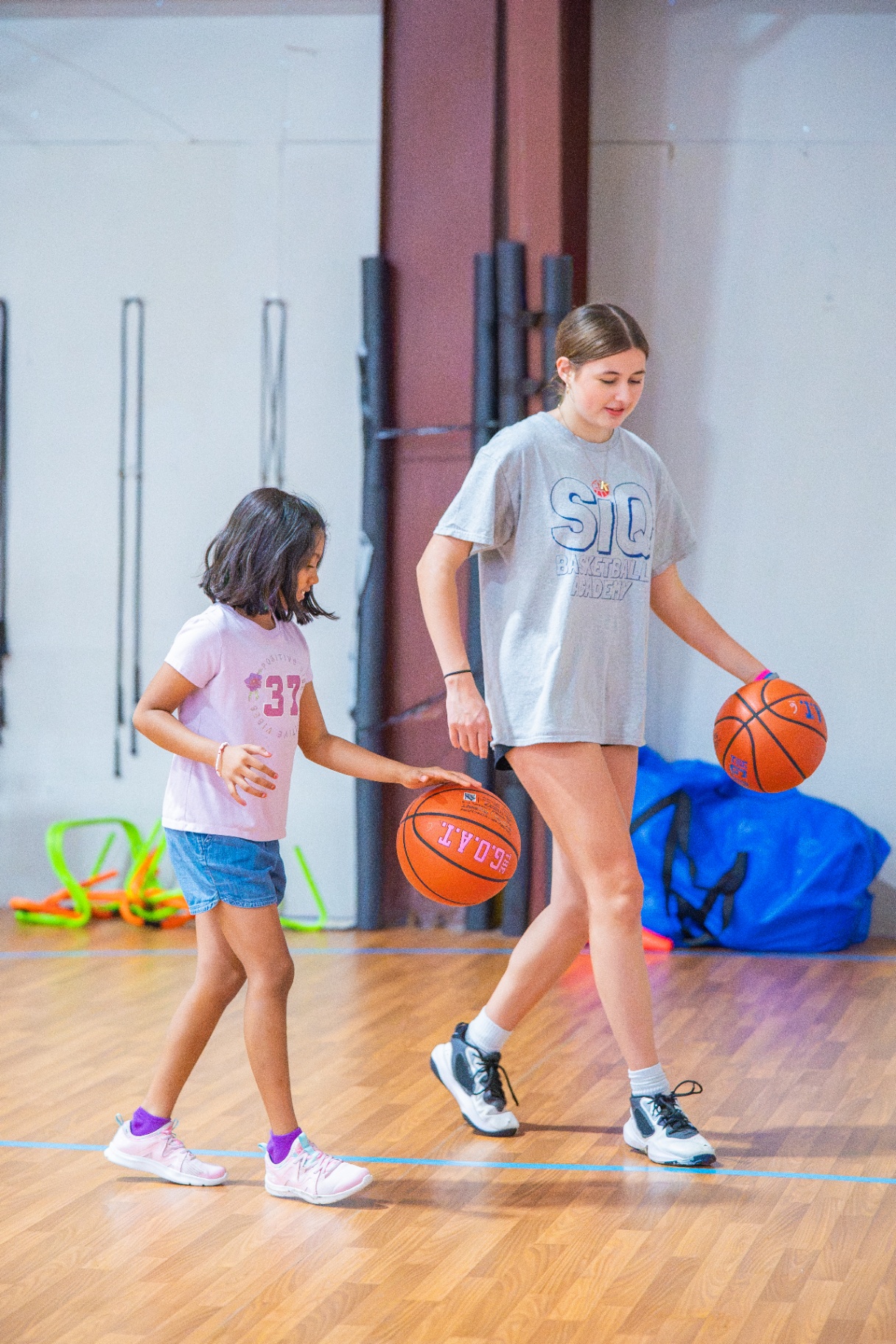 Older athlete guiding a younger player through a live dribbling drill