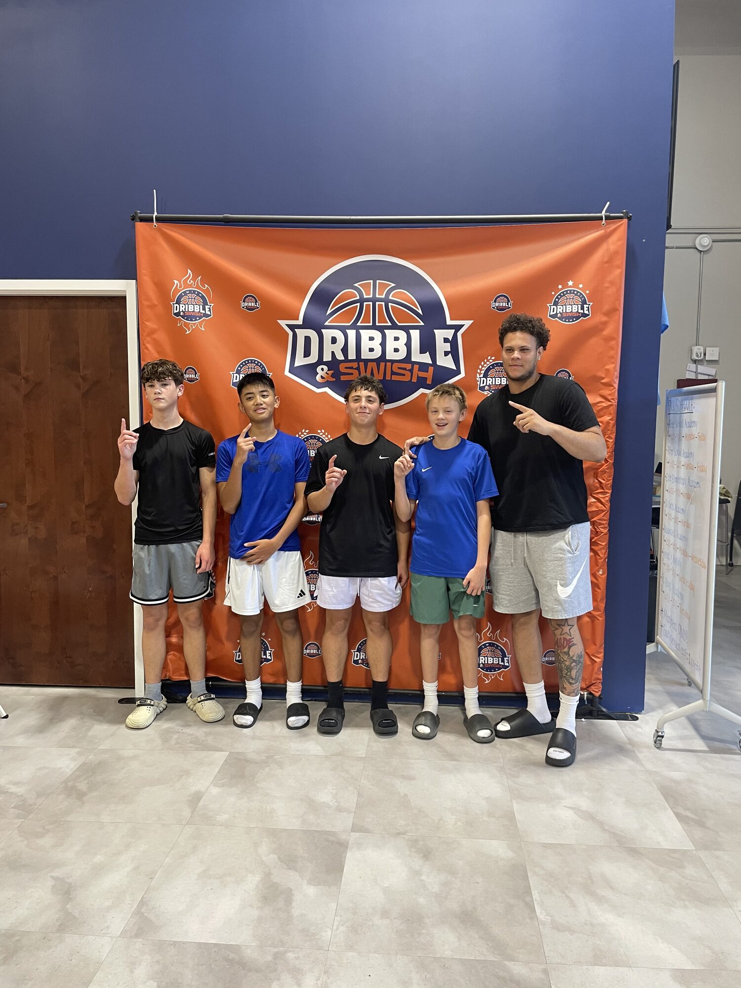Group of athletes posing in front of the Dribble & Swish banner after a session