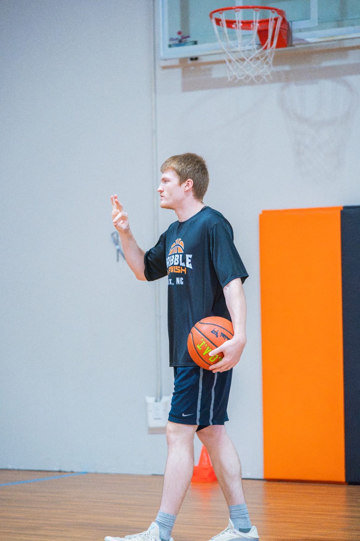 Coach giving an instruction cue under the basket with a ball tucked at his side