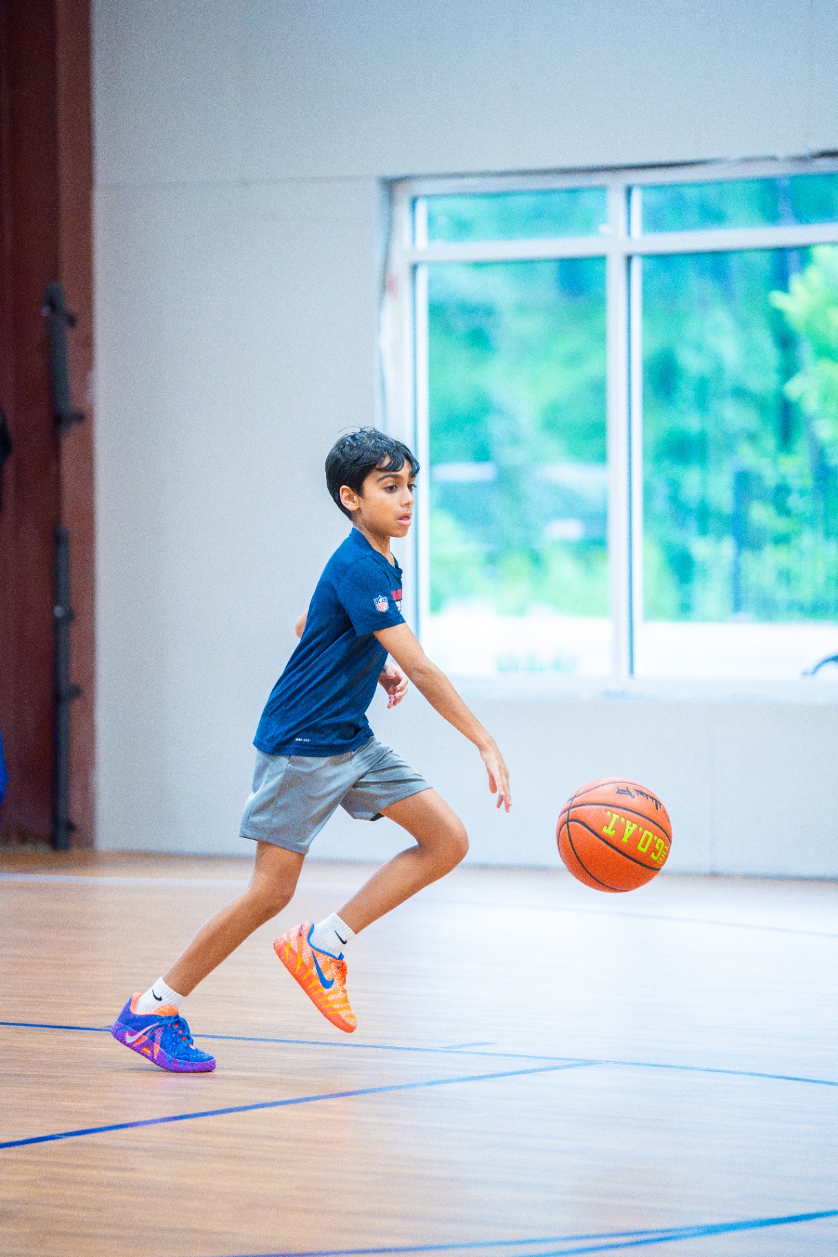 Player controlling a live dribble on the open court next to a bright window