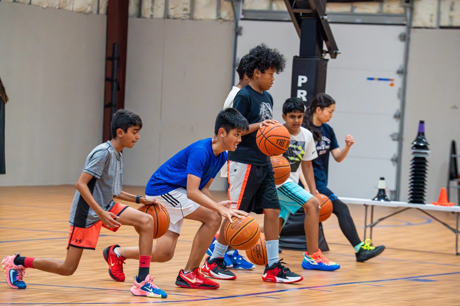 A line of athletes running a ball-handling drill together on the court