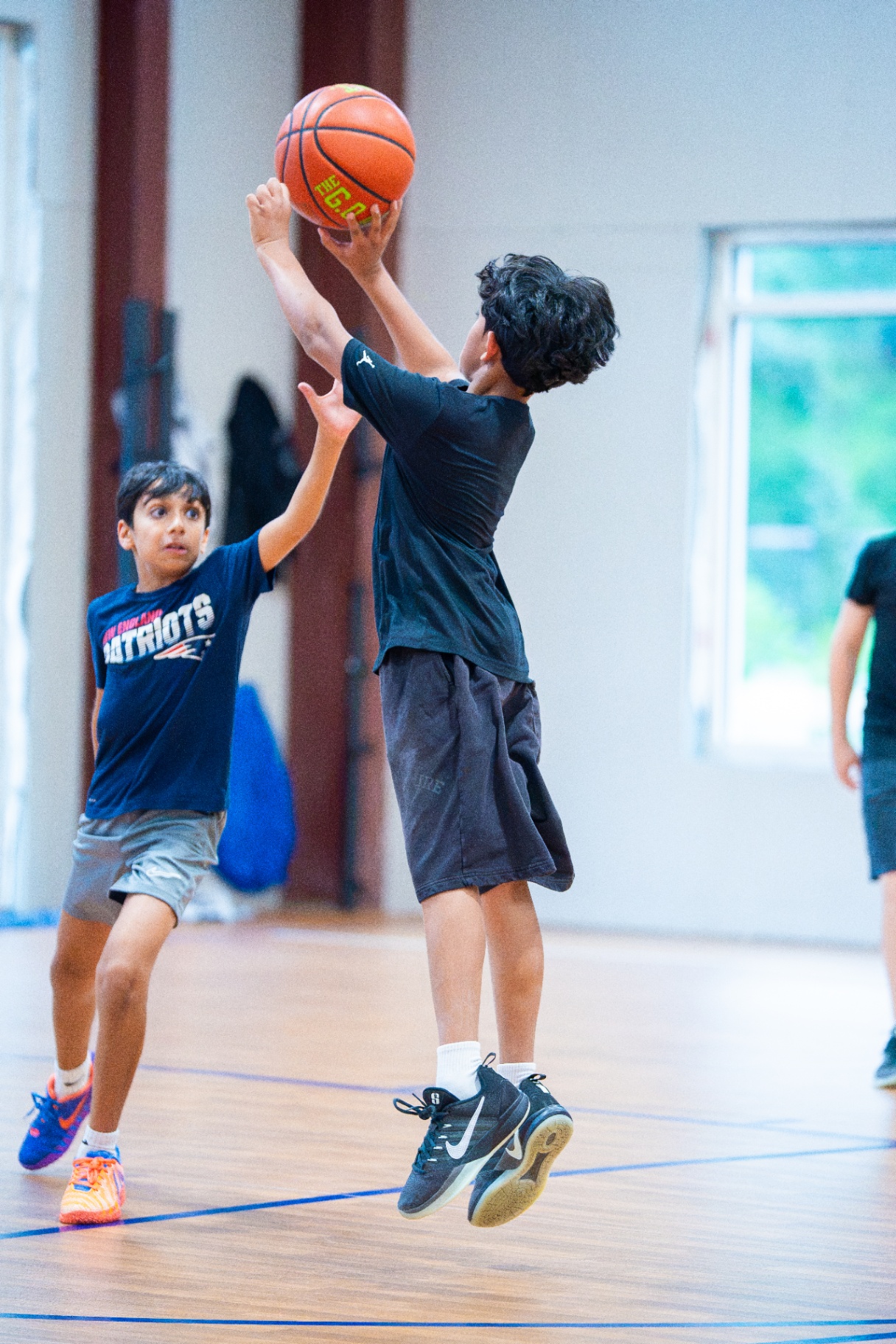 Athlete rising up for a mid-range jumper as a defender closes out