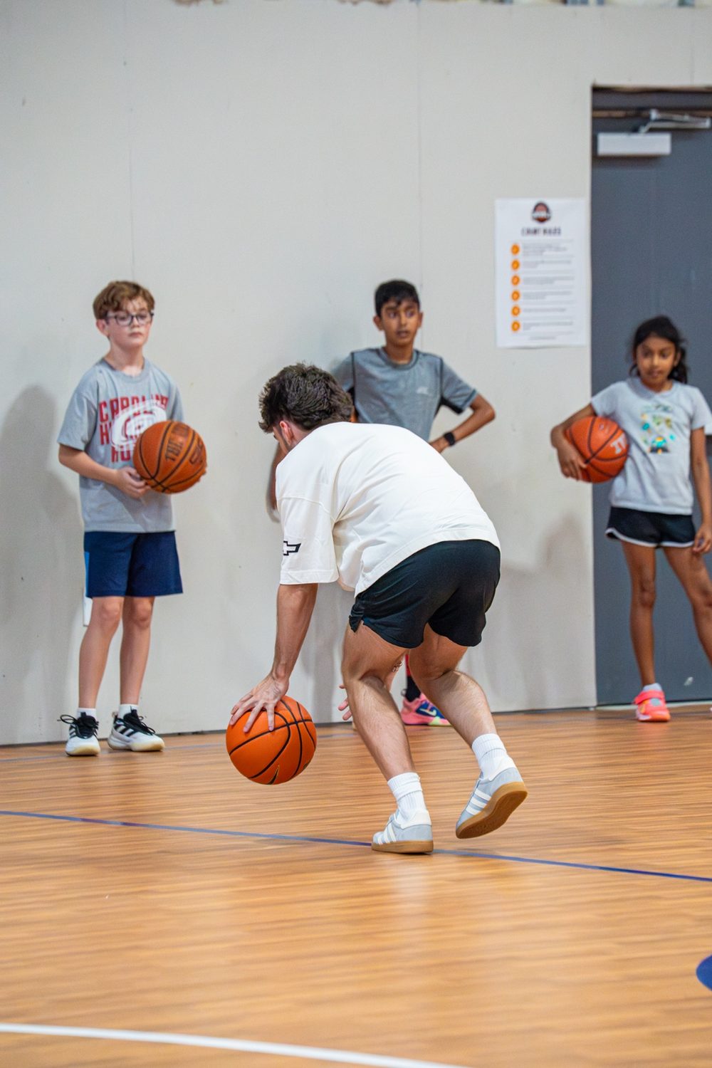 A coach demonstrating a low dribble move for a group of young athletes