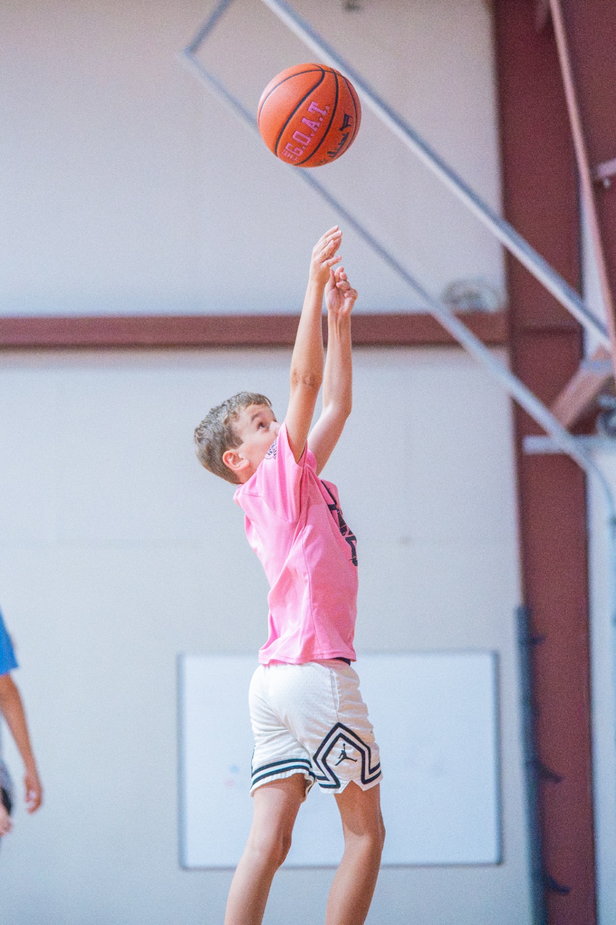 Young player in a pink jersey elevating for a jump shot with high follow-through