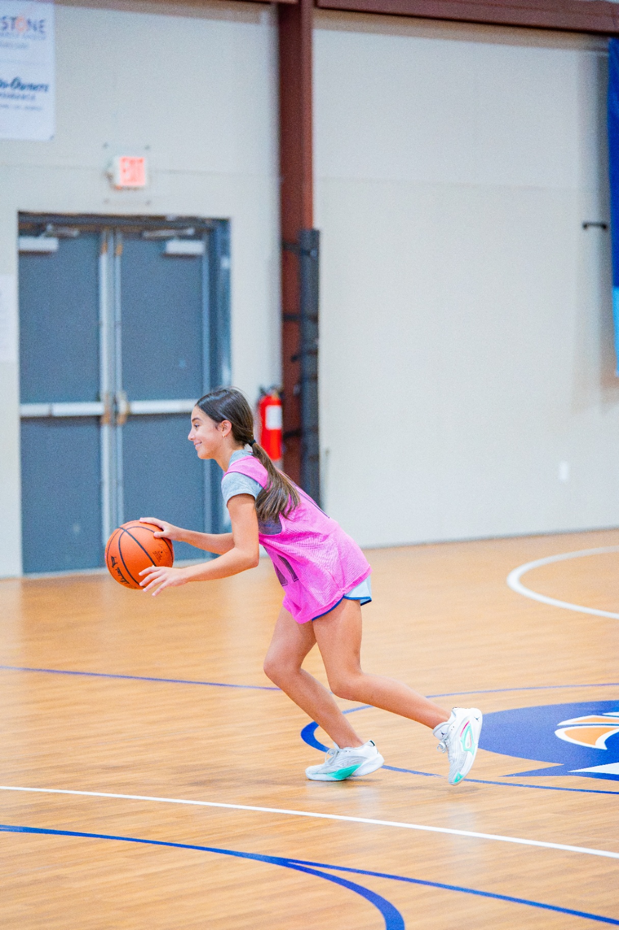 Athlete in a pink pinnie changing direction with the ball on a fast break