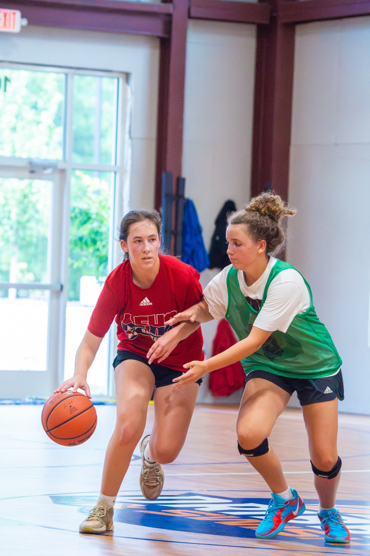 Ball-handler driving past a defender in a green pinnie during a live one-on-one